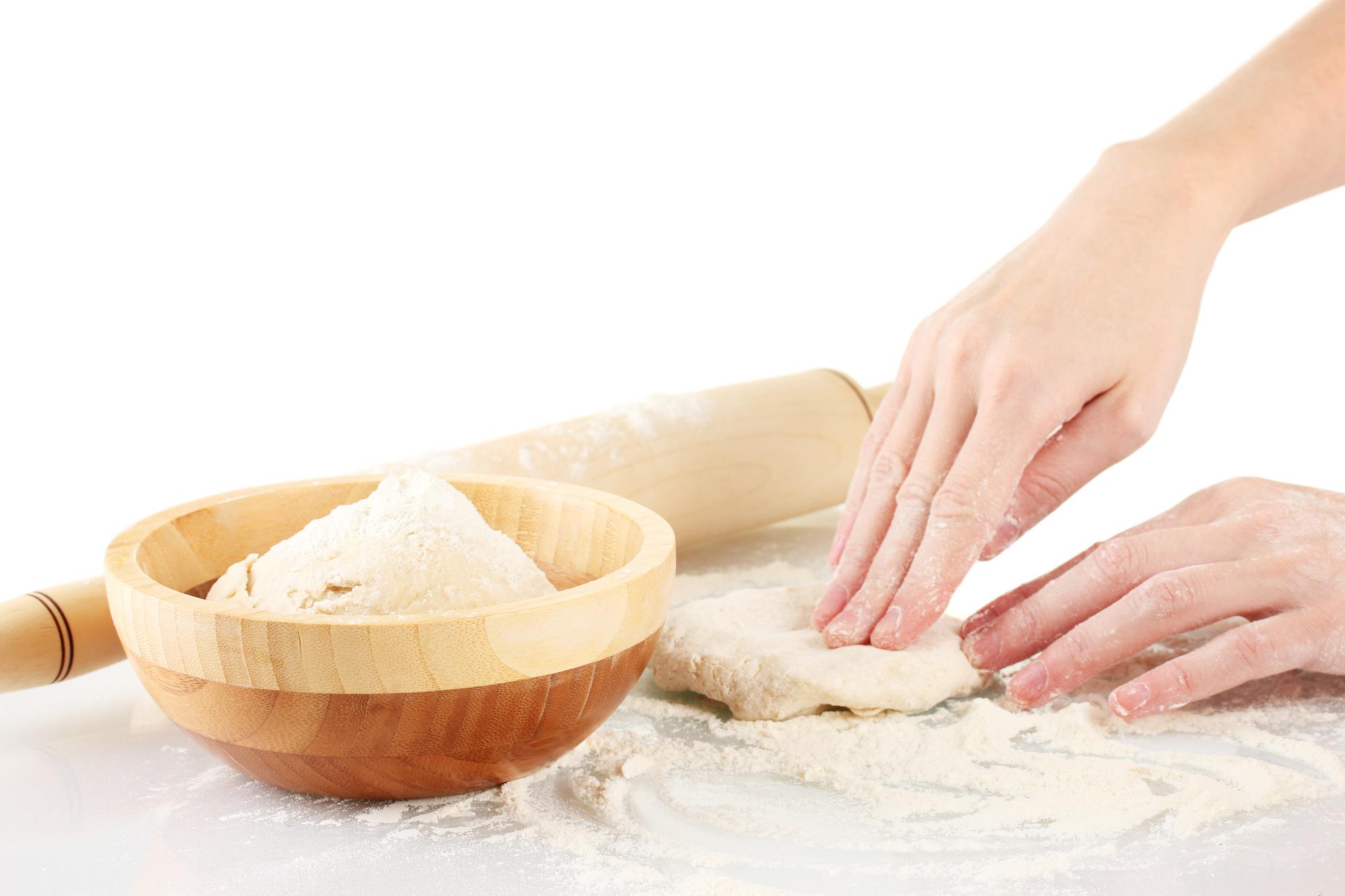 Close-up of hands kneading dough in warm light